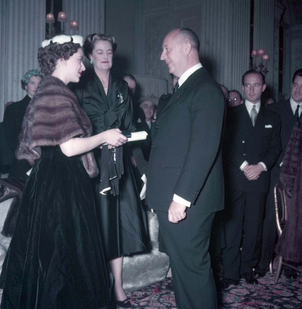 Princess Margaret (left), with the Duchess of Marlborough behind, presents Christian Dior with a scroll entitling him to Honorary Life Membership of the British Red Cross after the presentation of his Winter Collection at Blenheim Palace on 3rd November 1954. (Photo by Popperfoto/Getty Images)