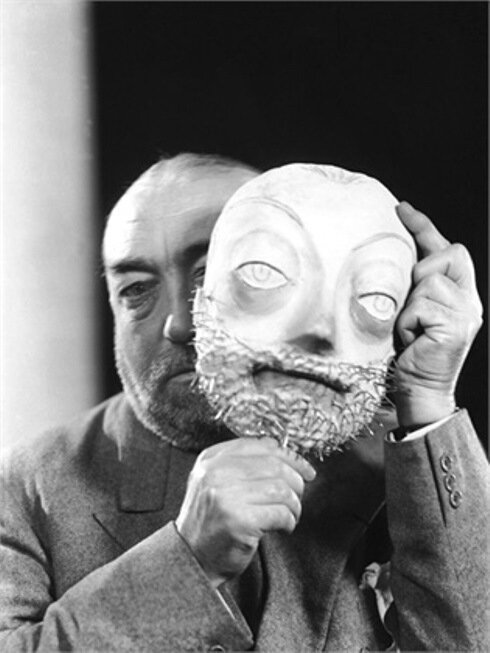 00/00/1935. The fashion designer Paul POIRET behind a bearded mask at his effigy, around 1935. Vers 1935, le couturier Paul POIRET derrière un masque barbu à son effigie.