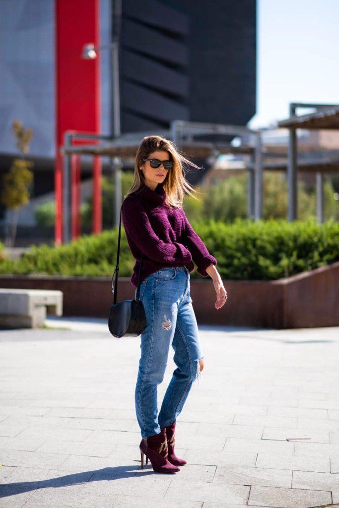 Девушка около лестнице в джинсах, свитере, очках и с сумкой