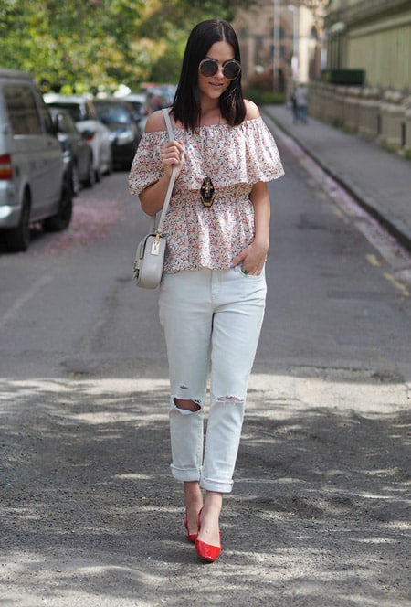 Модель в белых джинсах, топ с цветочным принтом, маленькая сумочка
