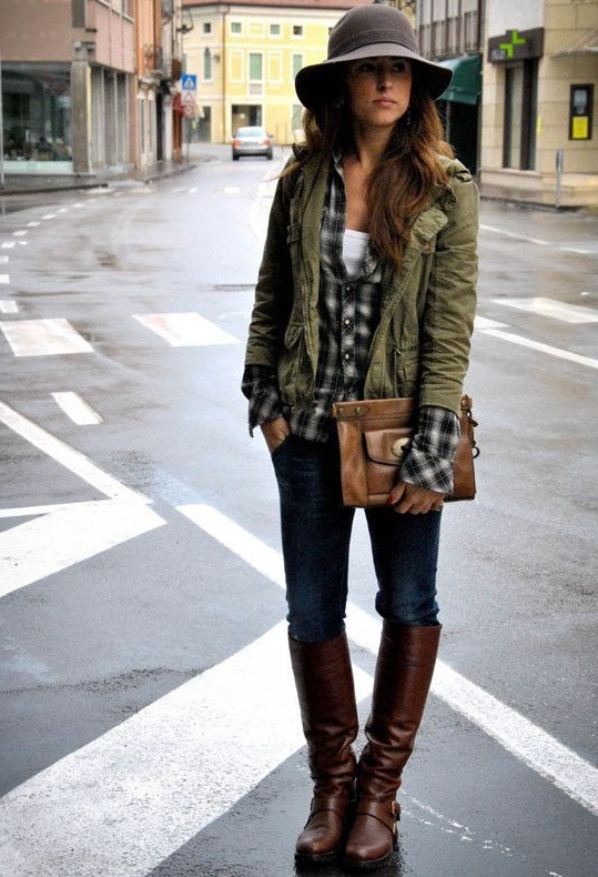 Девушка в куртке цвета хаки, джинсах и сапогах до колена в стиле милитари