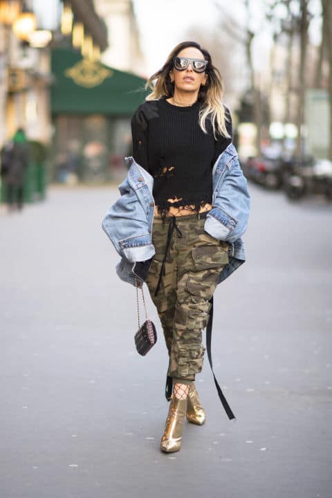 Девушка в брюках милитари, черный джемпер, джинсовая куртка и золотые боильоны