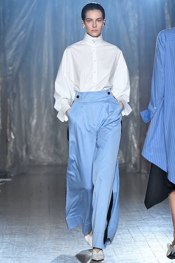 Модель в белой рубашке и голубых брюках палаццо